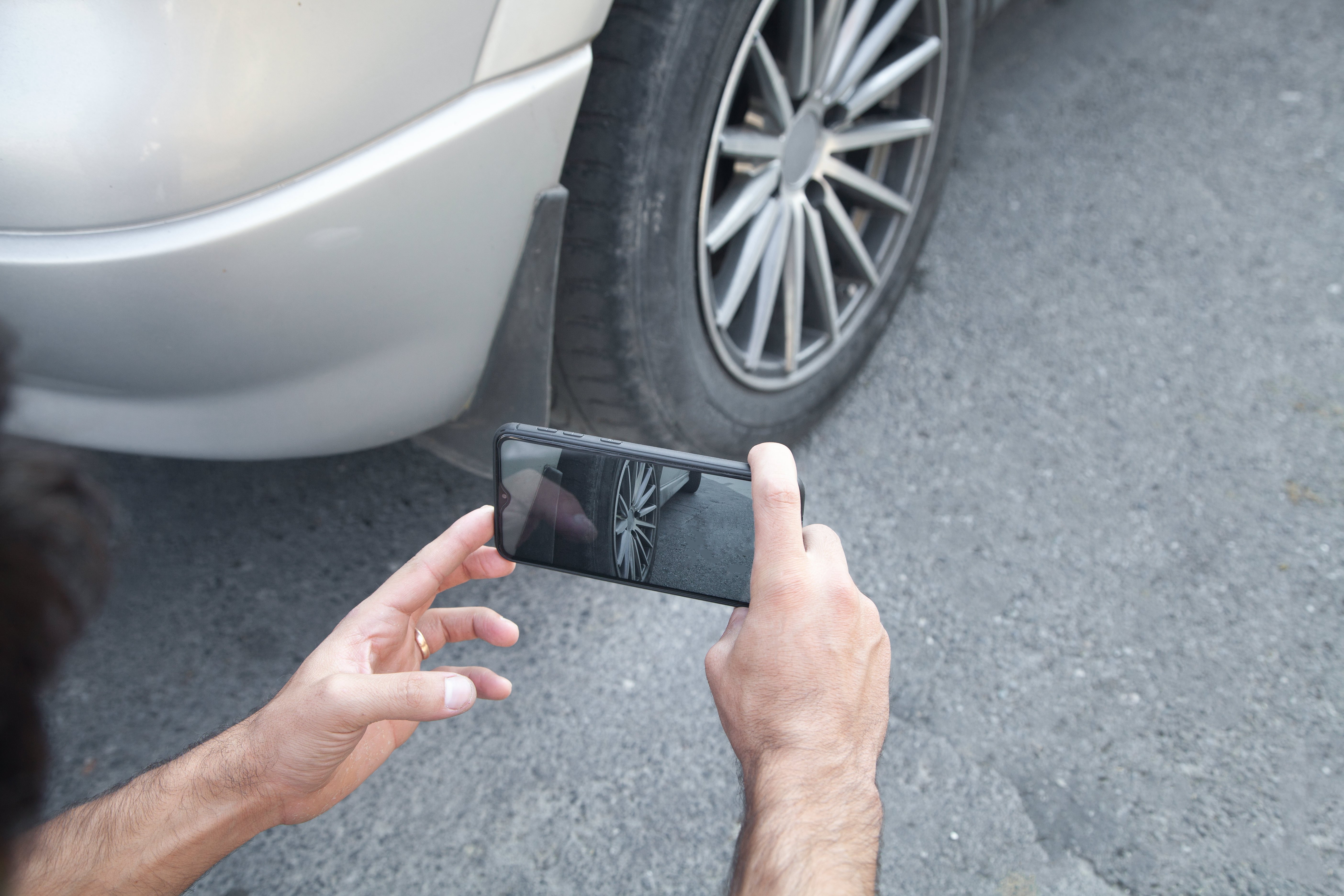 Pessoa tirando uma foto de uma roda de carro em seu telefone